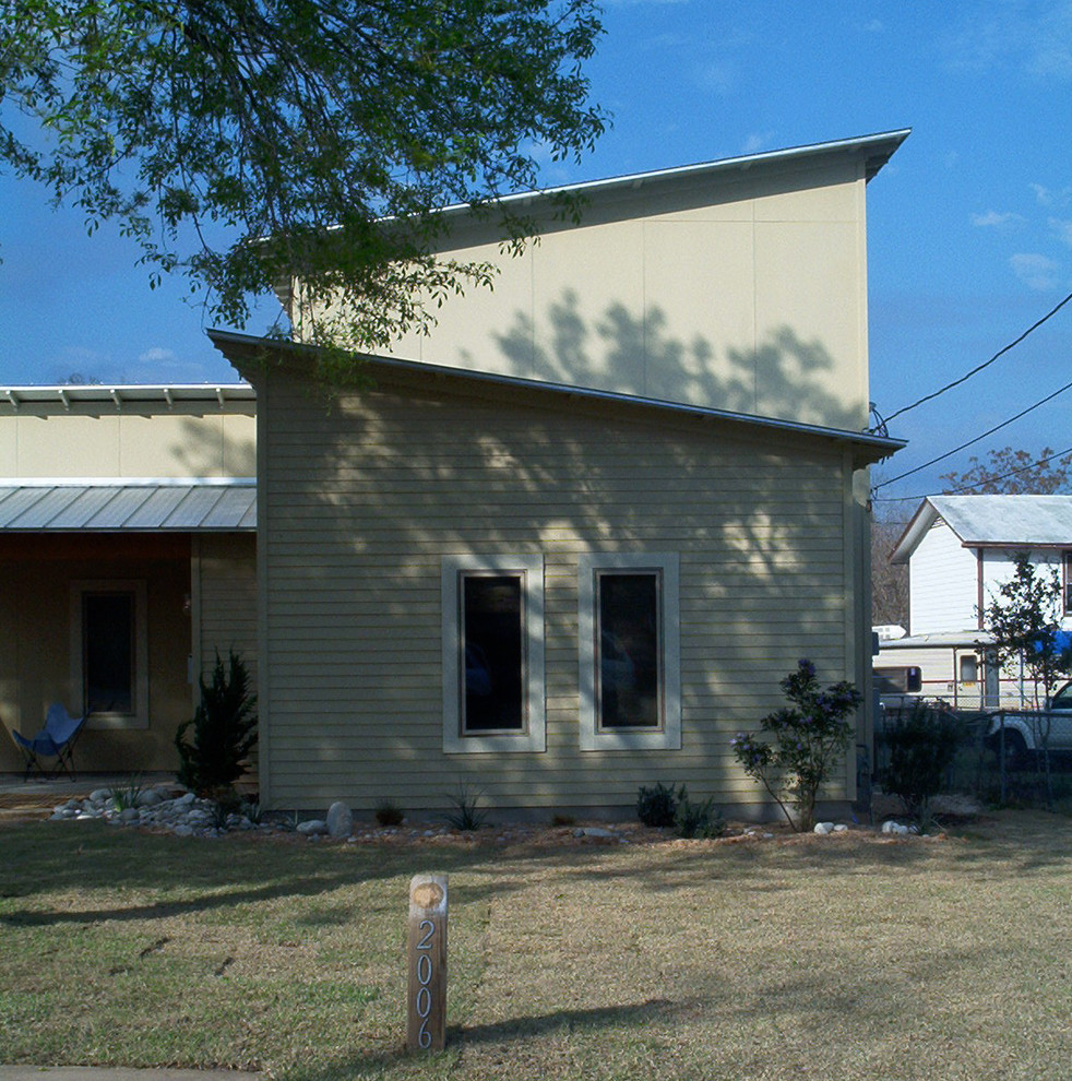 Ejemplo de fachada de casa beige vintage de tamaño medio de dos plantas con revestimiento de madera, tejado de un solo tendido y tejado de metal