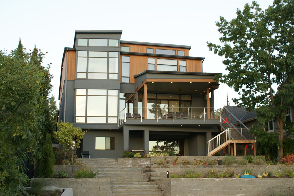 Foto della facciata di una casa grande grigia moderna a tre piani con rivestimenti misti e tetto piano