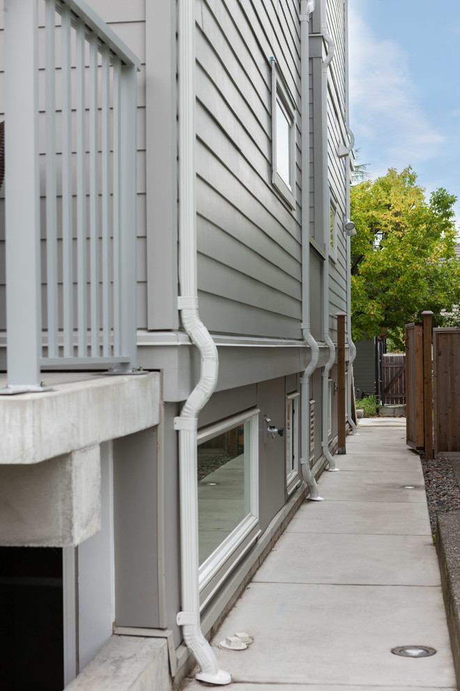 Modelo de fachada gris moderna de tamaño medio de dos plantas con revestimiento de aglomerado de cemento
