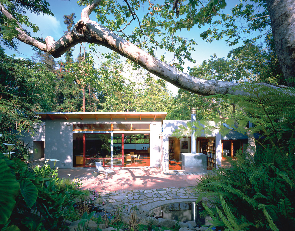 На фото: маленький, одноэтажный, серый дом в стиле модернизм с облицовкой из цементной штукатурки и односкатной крышей для на участке и в саду