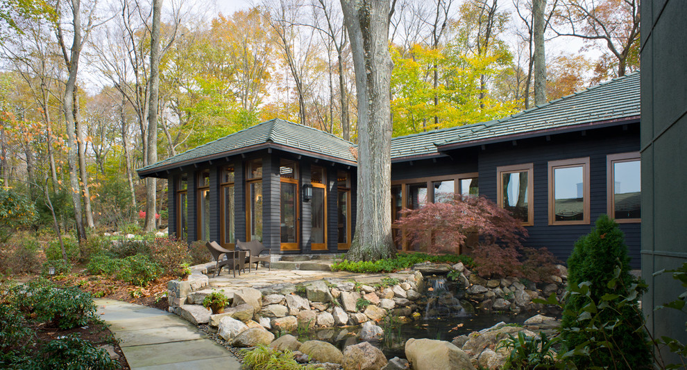 Photo of a contemporary bungalow house exterior in New York with wood cladding and a hip roof.