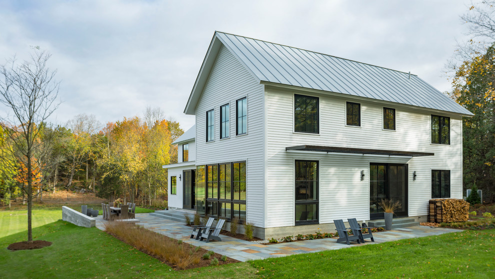Réalisation d'une grande façade de maison blanche minimaliste en bois à deux étages et plus avec un toit à deux pans et un toit en métal.