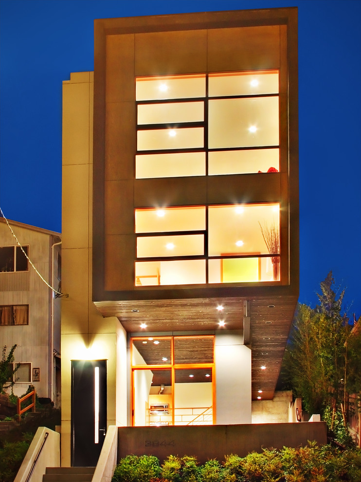 Immagine della facciata di una casa contemporanea a tre piani con terreno in pendenza
