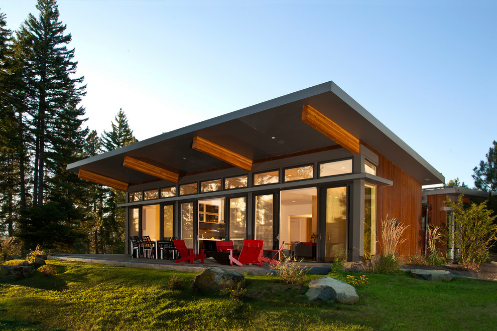 На фото: одноэтажный, деревянный, коричневый дом среднего размера в стиле модернизм с односкатной крышей