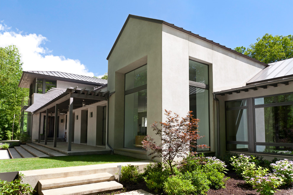 Large contemporary beige two-story stucco exterior home idea in Nashville with a metal roof