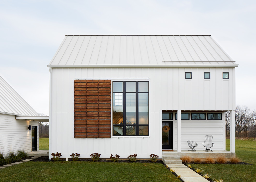 Exemple d'une façade de maison blanche nature de taille moyenne et à un étage avec un toit à quatre pans et un toit en métal.