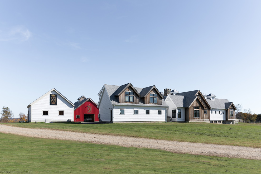 На фото: большой, двухэтажный, деревянный, разноцветный частный загородный дом в стиле кантри с двускатной крышей и крышей из смешанных материалов
