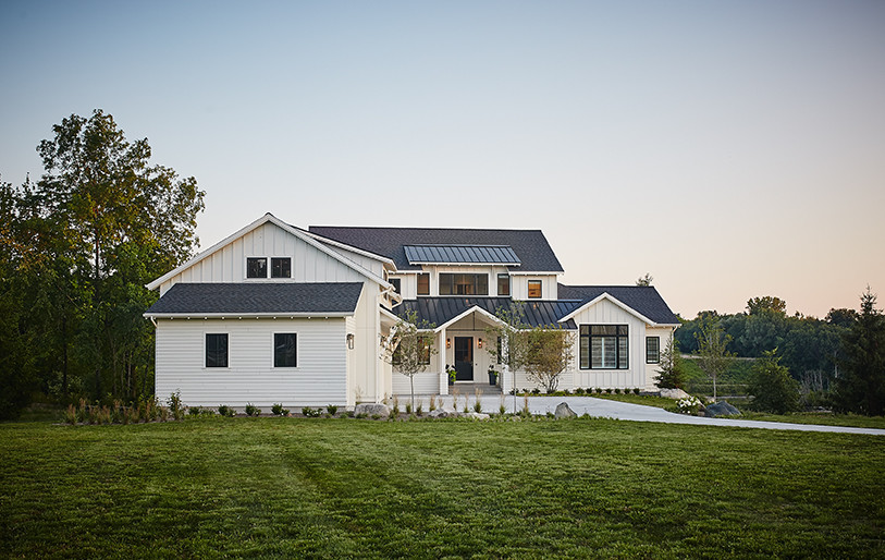 Réalisation d'une grande façade de maison blanche champêtre en panneau de béton fibré à un étage avec un toit à deux pans.