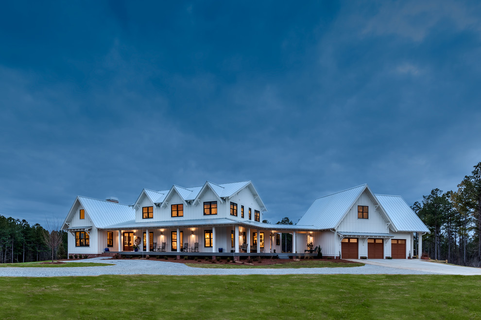 Cette image montre une grande façade de maison blanche rustique à un étage avec un revêtement mixte et un toit en métal.