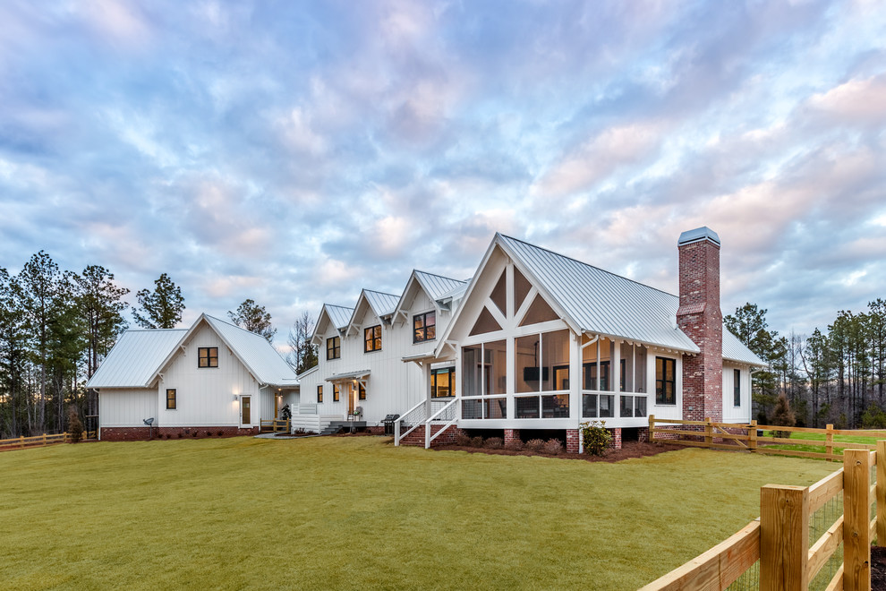 Foto della villa grande bianca country a due piani con rivestimenti misti e copertura in metallo o lamiera