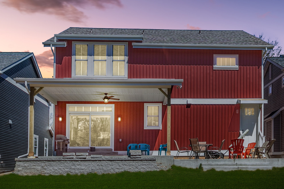 Cette image montre une façade de maison rouge rustique en panneau de béton fibré de taille moyenne et à un étage avec un toit à deux pans et un toit en métal.