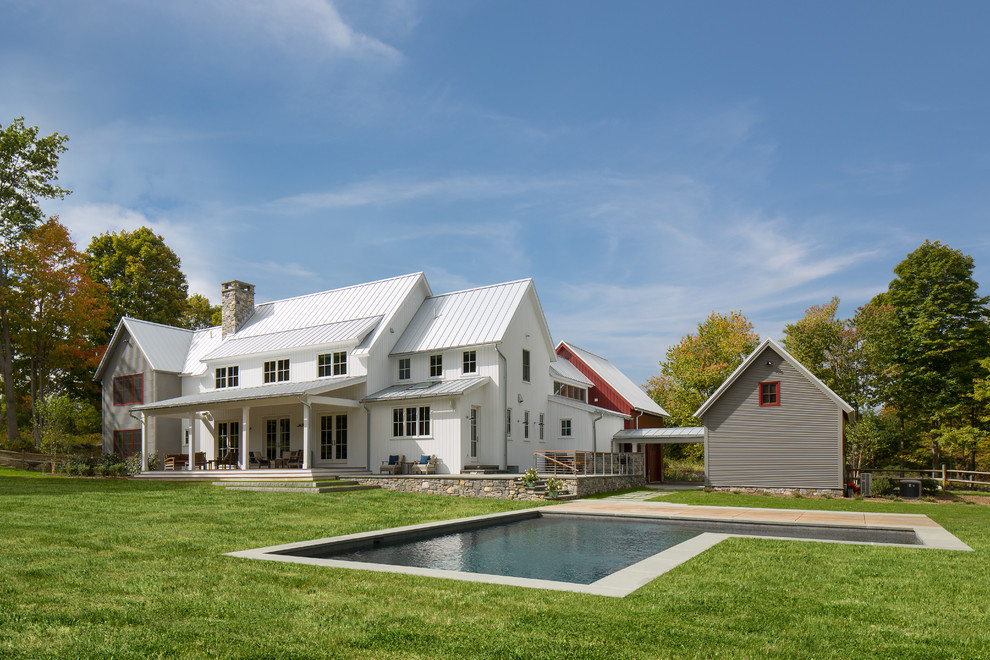 Aménagement d'une grande façade de maison blanche campagne à un étage avec un revêtement mixte et un toit à deux pans.