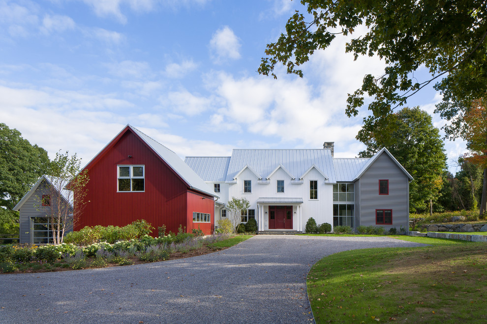 Foto della facciata di una casa grande bianca country a due piani con rivestimenti misti, tetto a capanna e abbinamento di colori