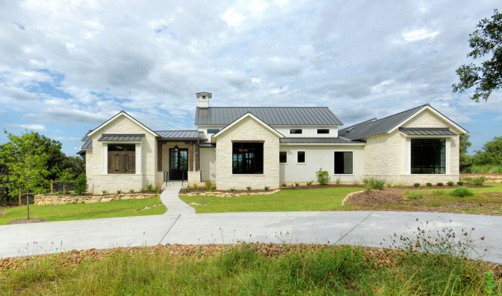 Ispirazione per la facciata di una casa bianca country a un piano di medie dimensioni con rivestimento in pietra e copertura in metallo o lamiera