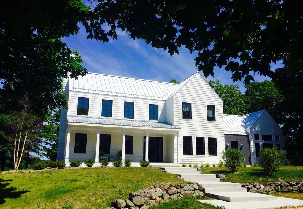 Cette image montre une grande façade de maison blanche rustique à un étage avec un toit à deux pans et un toit en métal.