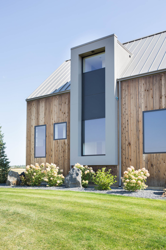 Foto de fachada de casa moderna grande de tres plantas con revestimiento de madera, tejado a dos aguas y tejado de metal