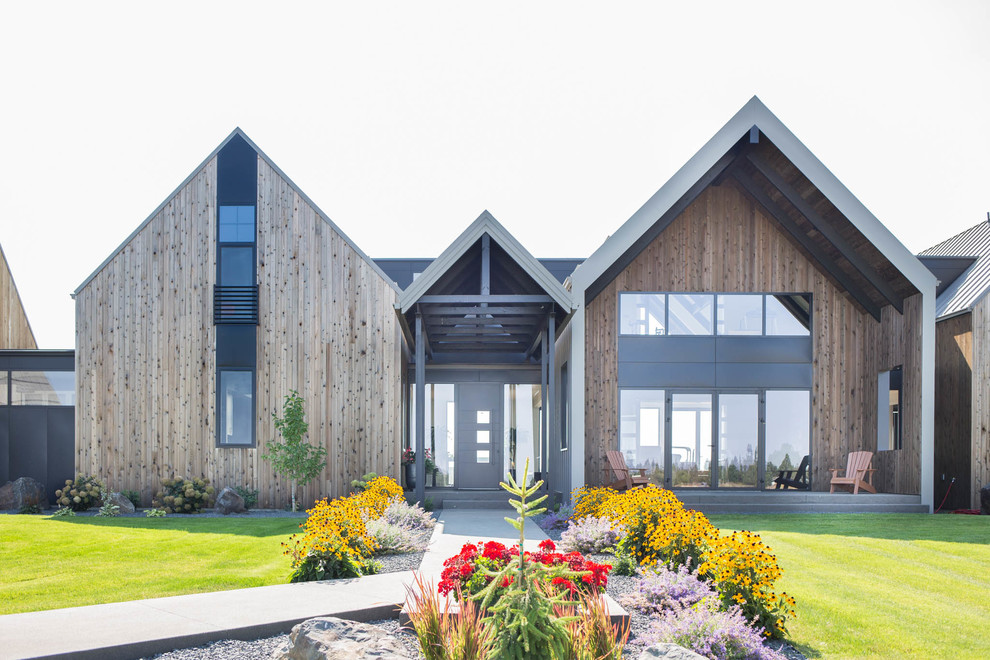 Cette photo montre une grande façade de maison moderne en bois à deux étages et plus avec un toit à deux pans et un toit en métal.