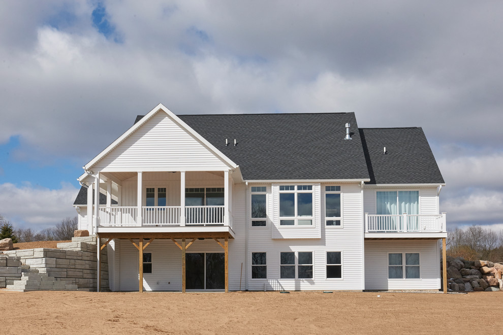 Foto de fachada de casa blanca de estilo de casa de campo grande a niveles con revestimiento de madera, tejado a dos aguas y tejado de teja de madera
