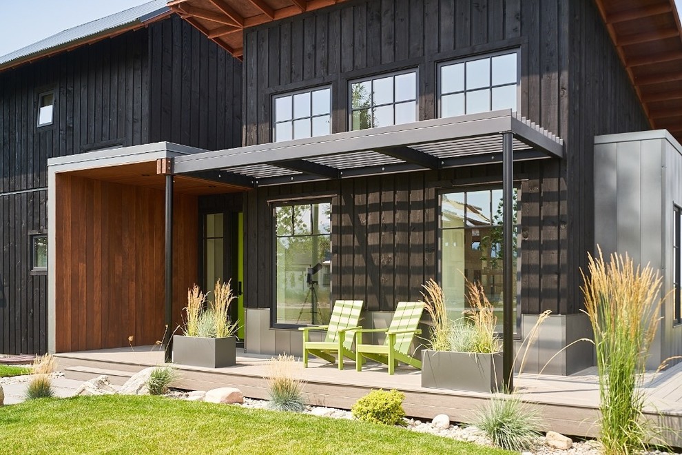 Diseño de fachada de casa negra de estilo de casa de campo de dos plantas con revestimiento de madera y tejado de metal