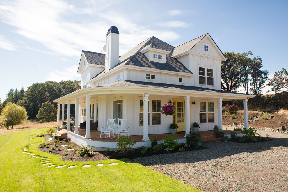 Foto della villa bianca country a due piani di medie dimensioni con tetto a padiglione e copertura a scandole