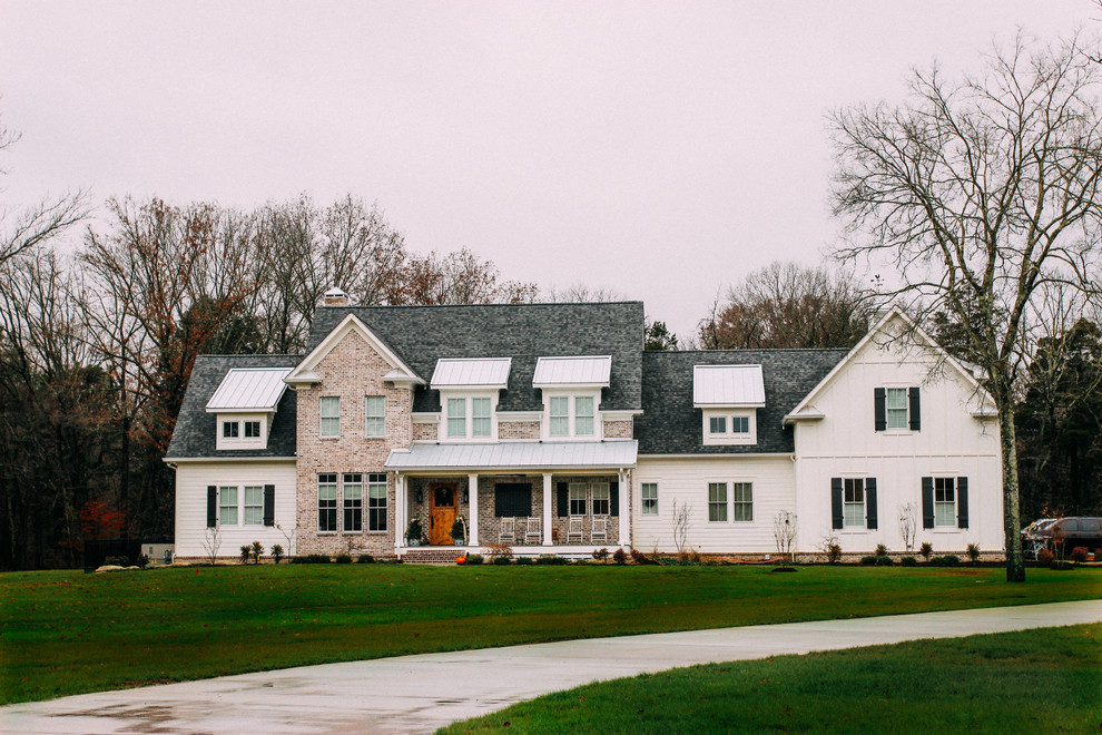 Foto della villa grande bianca country a due piani con rivestimenti misti, tetto a capanna e copertura mista