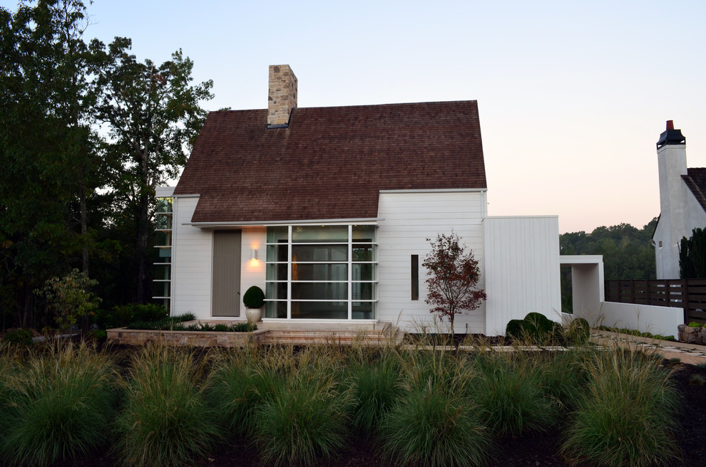 This is an example of a medium sized and white rural bungalow brick house exterior in Atlanta with a hip roof.