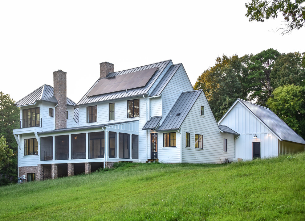 Cette photo montre une façade de maison blanche nature en panneau de béton fibré de taille moyenne et à deux étages et plus avec un toit à deux pans et un toit en métal.