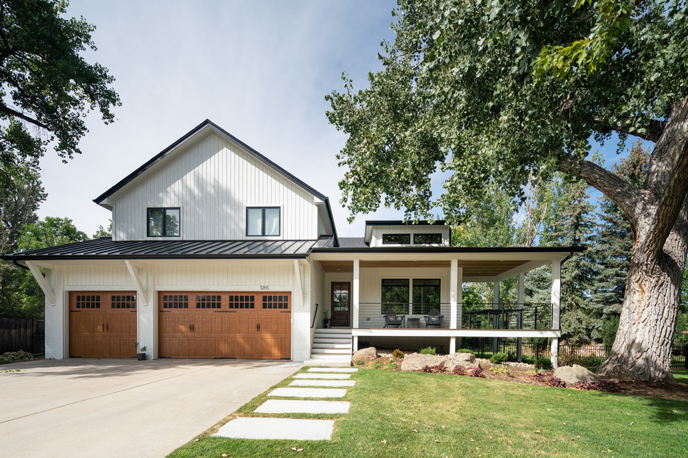 Cette photo montre une façade de maison blanche nature à deux étages et plus avec un revêtement mixte et un toit en métal.