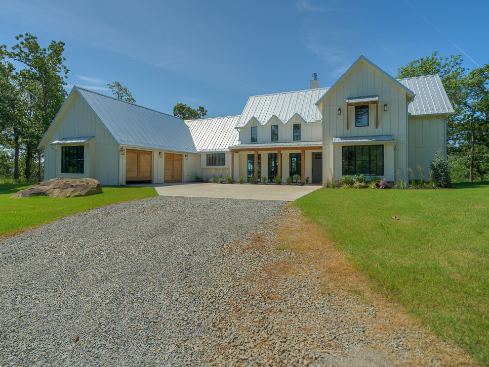 Foto della villa grande bianca country a due piani con rivestimento con lastre in cemento e copertura in metallo o lamiera