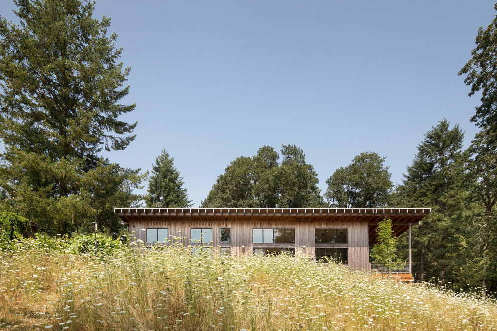 Idée de décoration pour une façade de maison marron champêtre en bois de plain-pied avec un toit en appentis et un toit en métal.