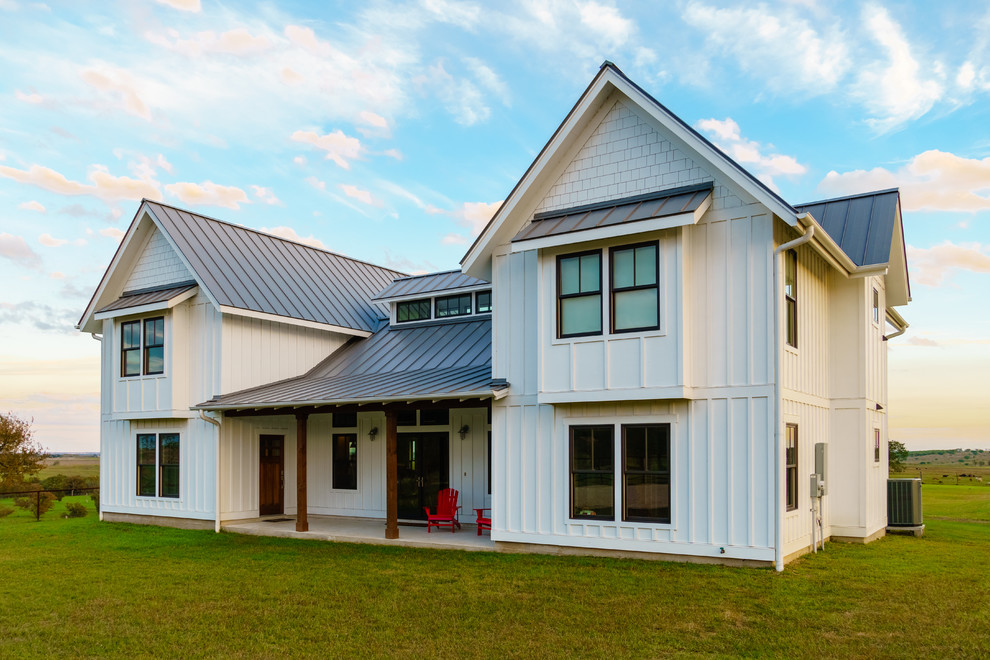 Cette photo montre une façade de maison blanche nature en panneau de béton fibré de taille moyenne et à un étage avec un toit à deux pans et un toit en métal.