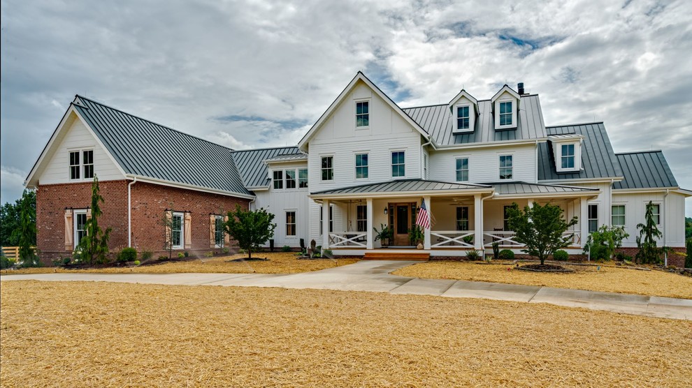 Esempio della villa grande multicolore country a un piano con rivestimenti misti, tetto a capanna e copertura in metallo o lamiera