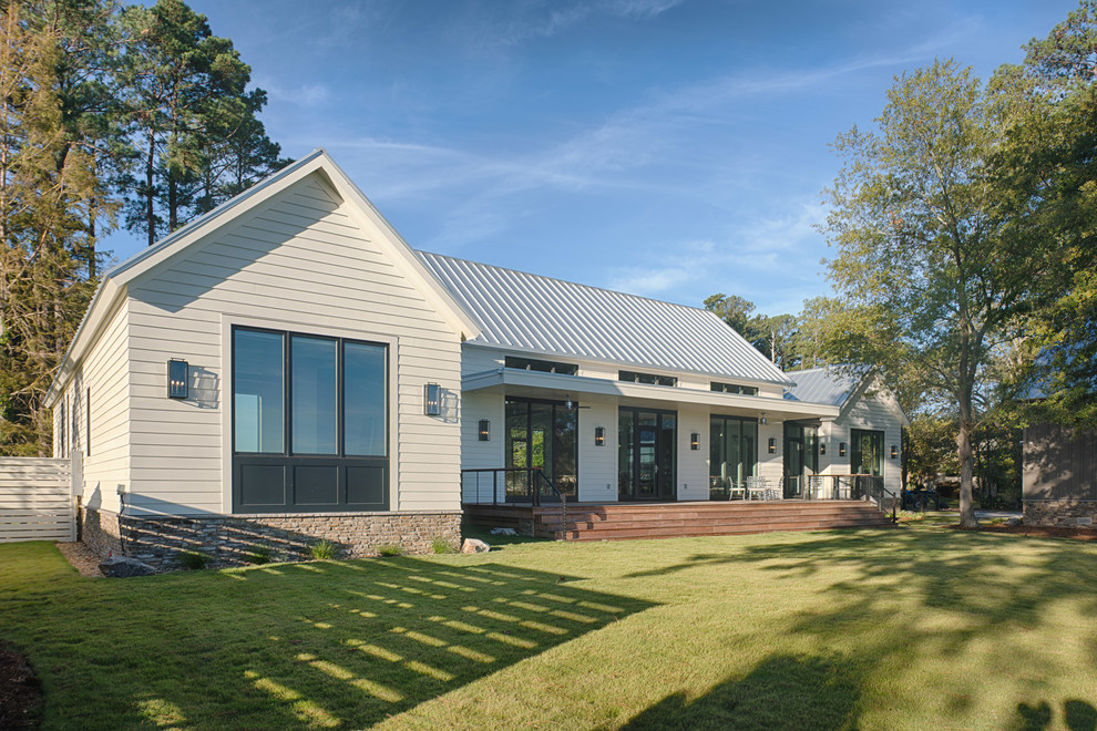 Imagen de fachada de casa blanca campestre de una planta con tejado a dos aguas y tejado de metal