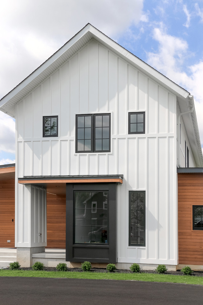 Imagen de fachada de casa blanca campestre de tamaño medio de dos plantas con tejado de un solo tendido, tejado de teja de madera y revestimientos combinados