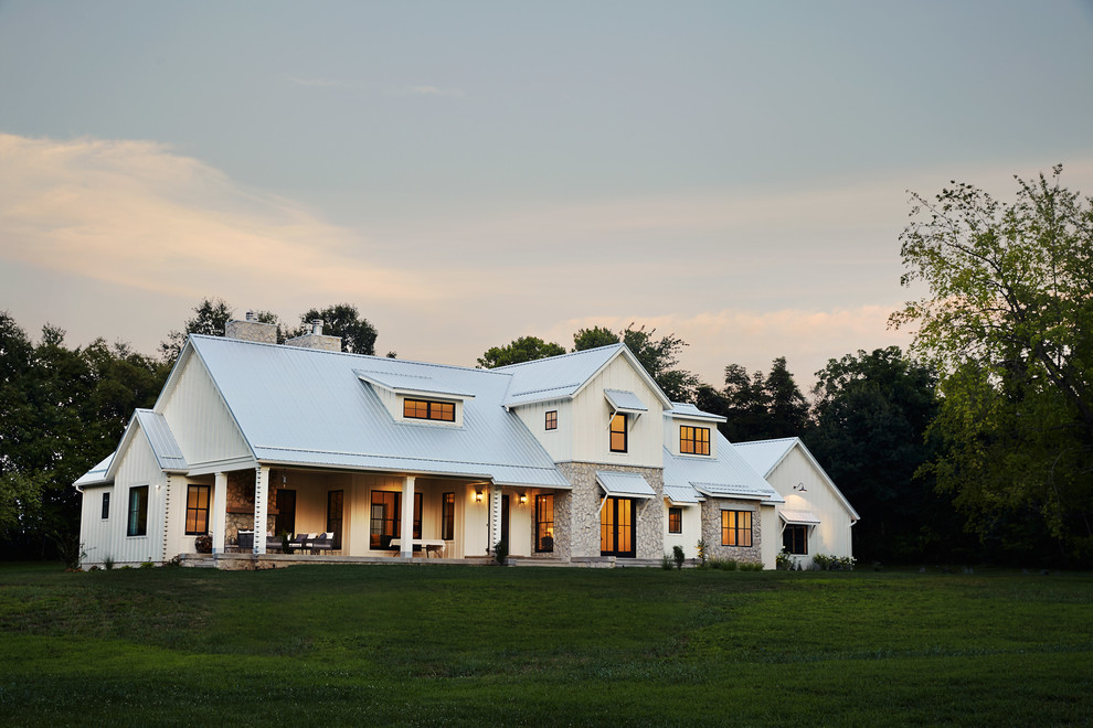 Ejemplo de fachada de casa blanca campestre grande de dos plantas con revestimiento de metal, tejado a dos aguas y tejado de metal