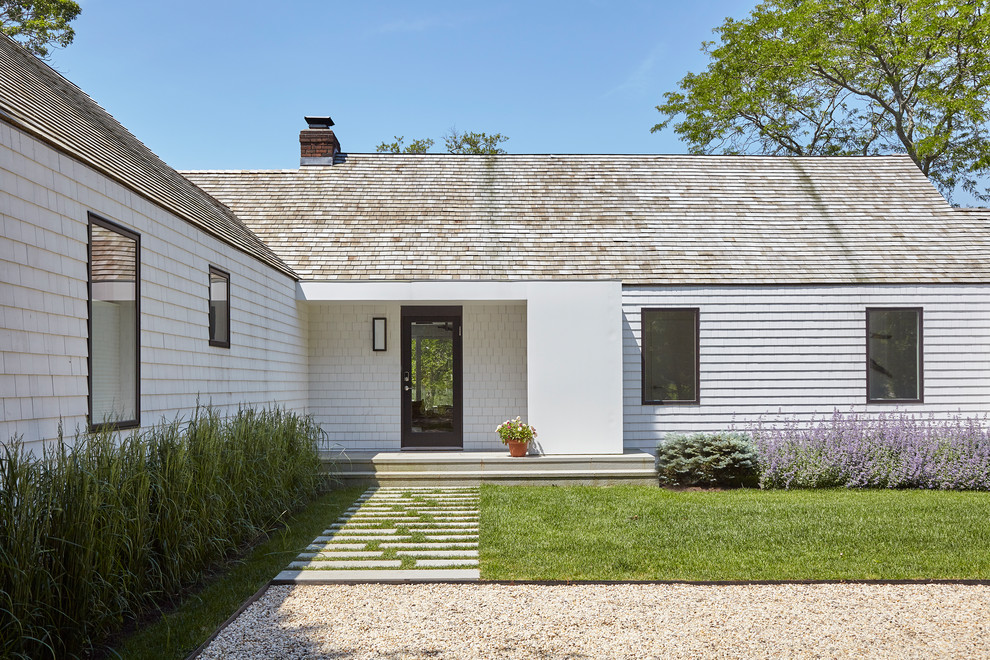 This is an example of a white farmhouse bungalow detached house in New York with wood cladding, a hip roof and a shingle roof.