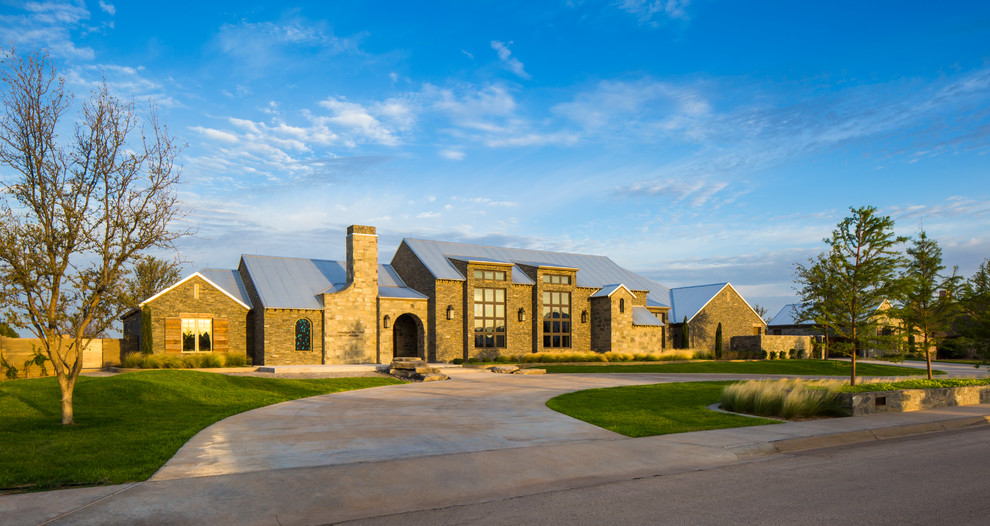 Example of a huge farmhouse gray three-story stone gable roof design in Austin