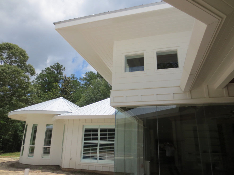 Cette image montre une grande façade de maison blanche minimaliste de plain-pied avec un revêtement mixte, un toit à deux pans et un toit en métal.