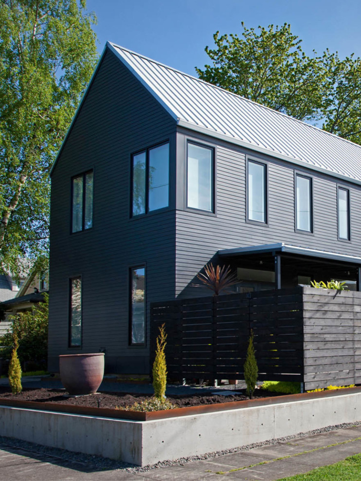 Exempel på ett stort modernt grått hus, med två våningar, vinylfasad, sadeltak och tak i metall