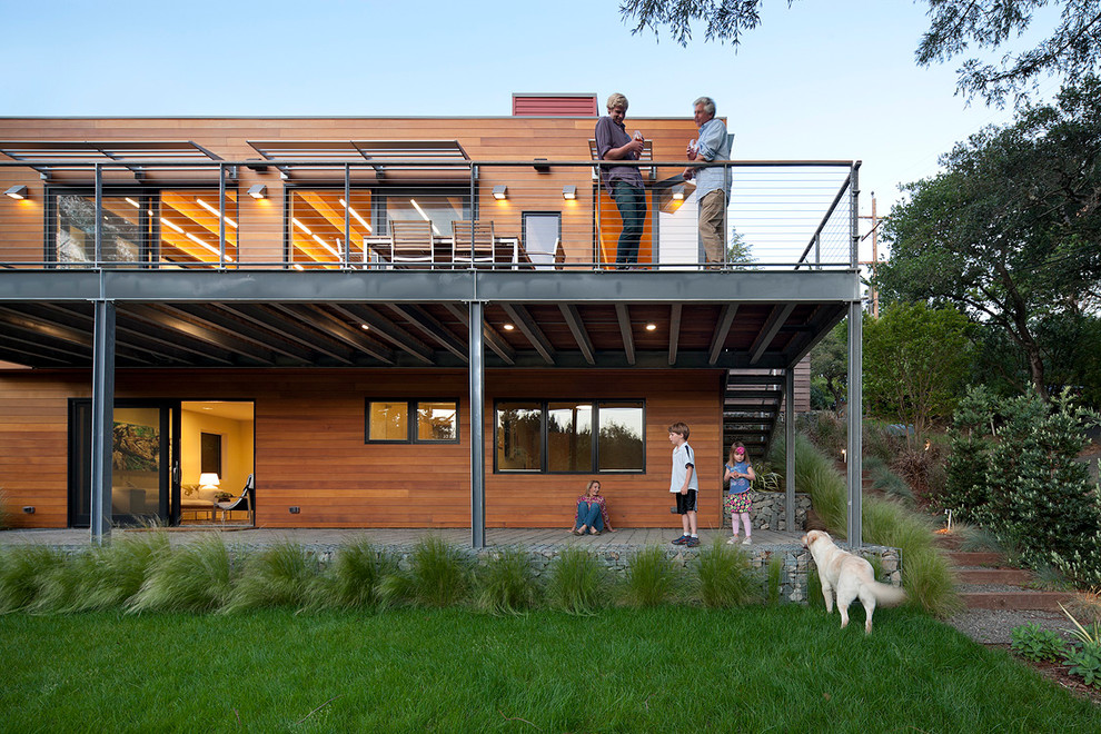 Immagine della facciata di una casa contemporanea con rivestimento in legno e terreno in pendenza