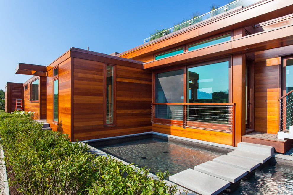 Cette photo montre une grande façade de maison marron moderne en bois de plain-pied.