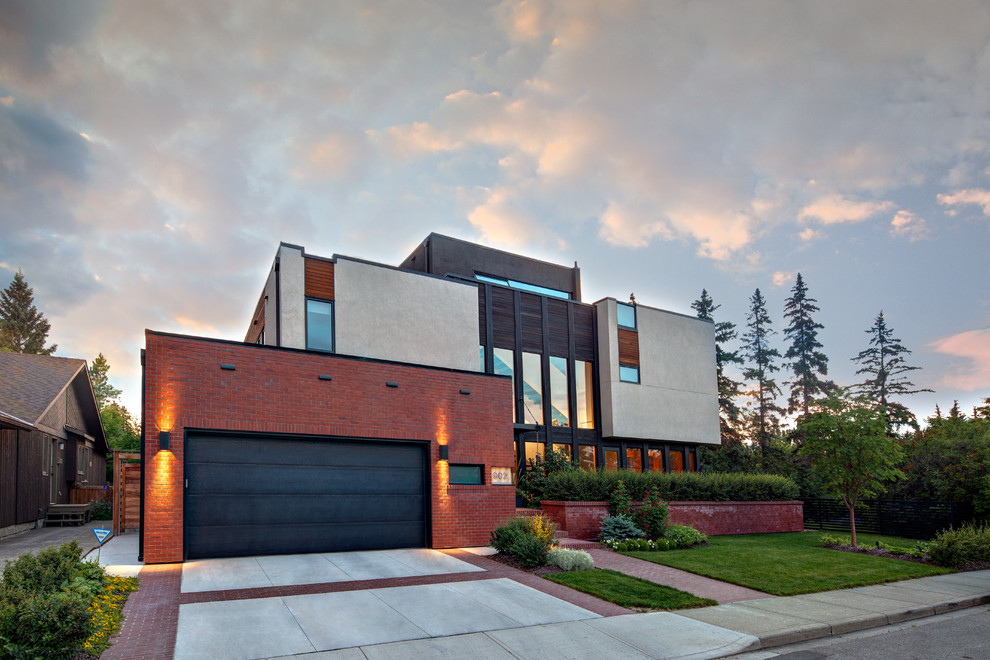 Photo of a large and red contemporary brick house exterior in Calgary with three floors.