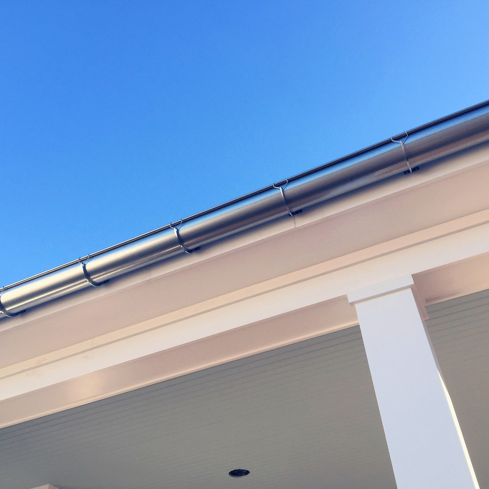 Réalisation d'une façade de maison blanche champêtre en panneau de béton fibré de taille moyenne et à un étage avec un toit en métal.
