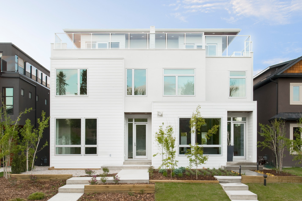 Inspiration for a white contemporary house exterior in Calgary with three floors.