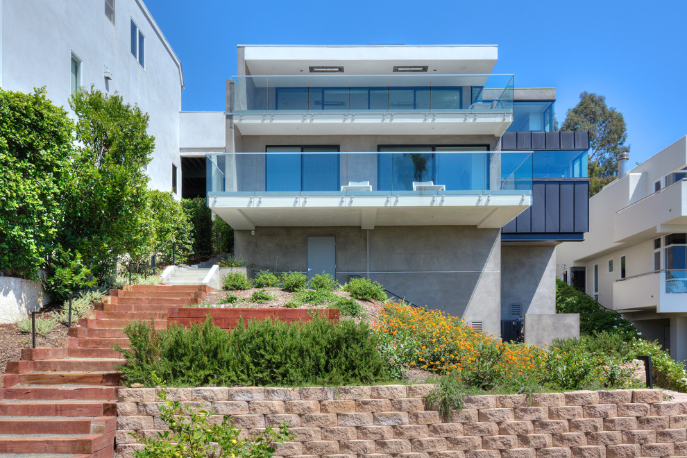Mittelgroßes, Zweistöckiges Maritimes Einfamilienhaus mit Betonfassade, grauer Fassadenfarbe, Flachdach und Blechdach in Orange County