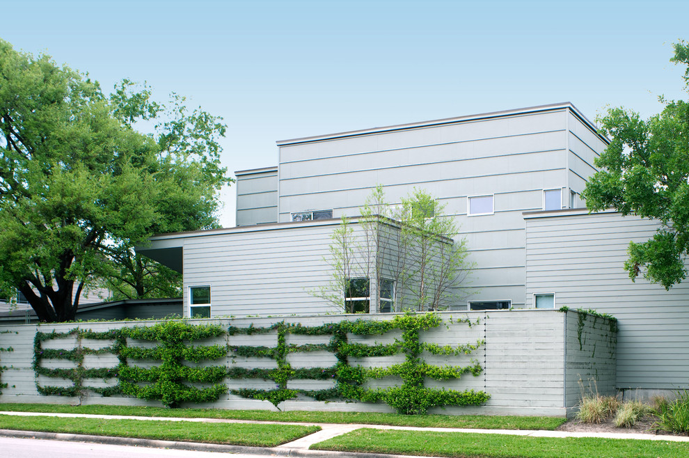 Cette photo montre une façade de maison grise moderne en panneau de béton fibré de taille moyenne et à un étage avec un toit plat.