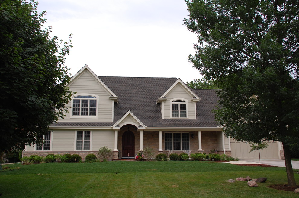 Cette image montre une façade de maison beige minimaliste en panneau de béton fibré à un étage et de taille moyenne avec un toit à deux pans et un toit en shingle.