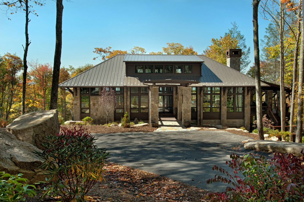 Imagen de fachada rústica de dos plantas con revestimiento de piedra, tejado a cuatro aguas y tejado de metal