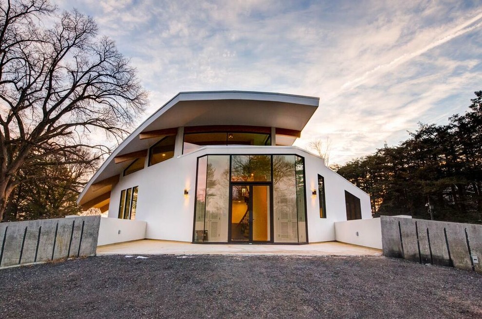 На фото: большой, двухэтажный, белый частный загородный дом в стиле модернизм с облицовкой из бетона и плоской крышей с