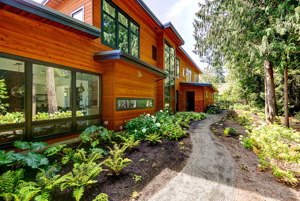 Идея дизайна: большой, двухэтажный, коричневый частный загородный дом в современном стиле с комбинированной облицовкой, плоской крышей и металлической крышей